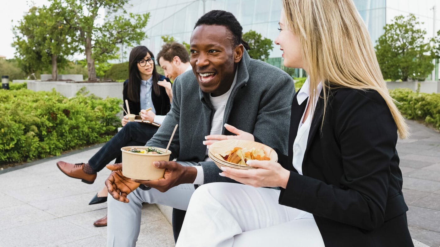 Happy multiracial business people having a lunch break outside office