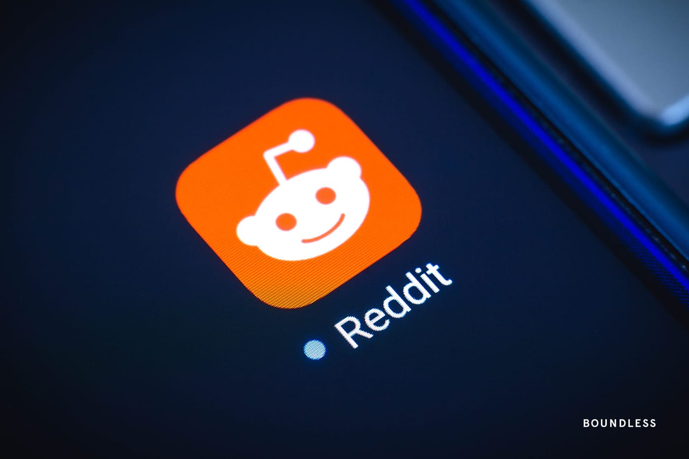 A close-up of the Reddit app on a dark smartphone screen with the Boundless Immigration wordmark logo in the bottom right-hand corner