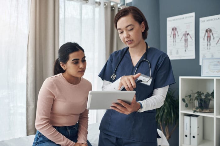 Photo of a young female doctor talking to a patient in an office.